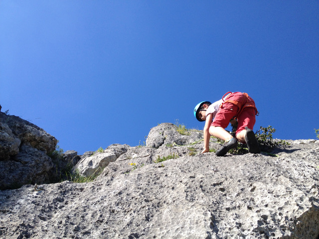 Enfant qui grimpe sur une falaise calcaire dans le département du Lot 