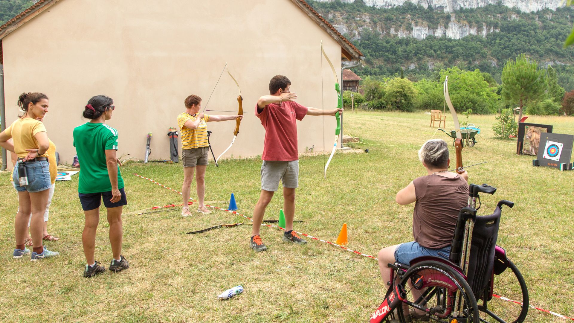 tir à l'arc avec une personne en fauteuil roulant et 2 personnes debout